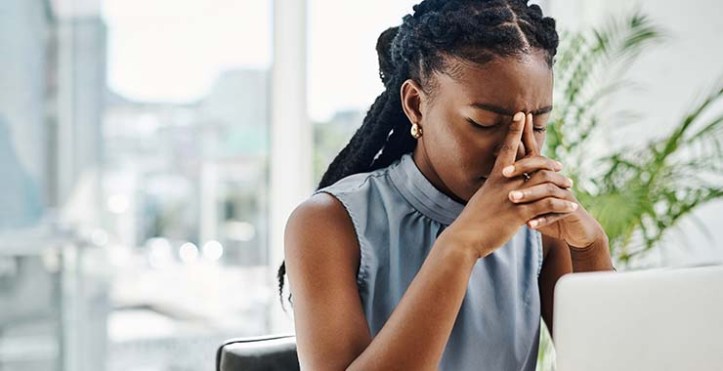 Young woman at computer displaying burnout and frustration